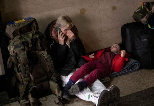 Pessoas estão se deslocando para o metrô em Kiev com mantimentos para se protegerem dos ataques russos à Ucrânia | Emilio Moneratti/AP

