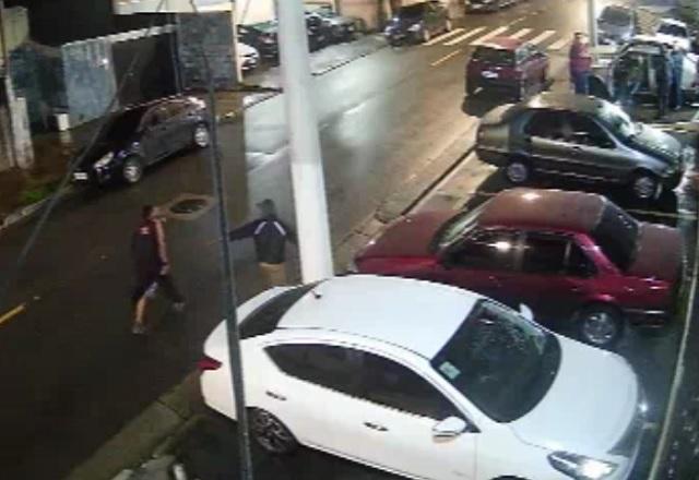 Vítima de disparo, ao lado do carro branco, busca socorro em rua da zona norte de SP | Reprodução/SBT
