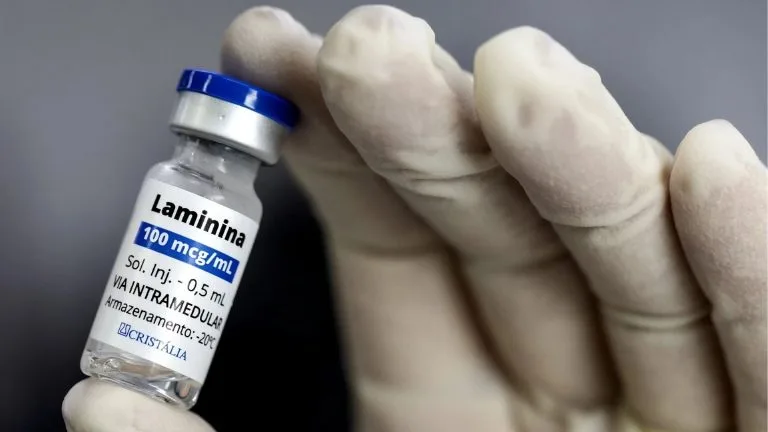 Ampola de polilaminina em mão com luva médica
